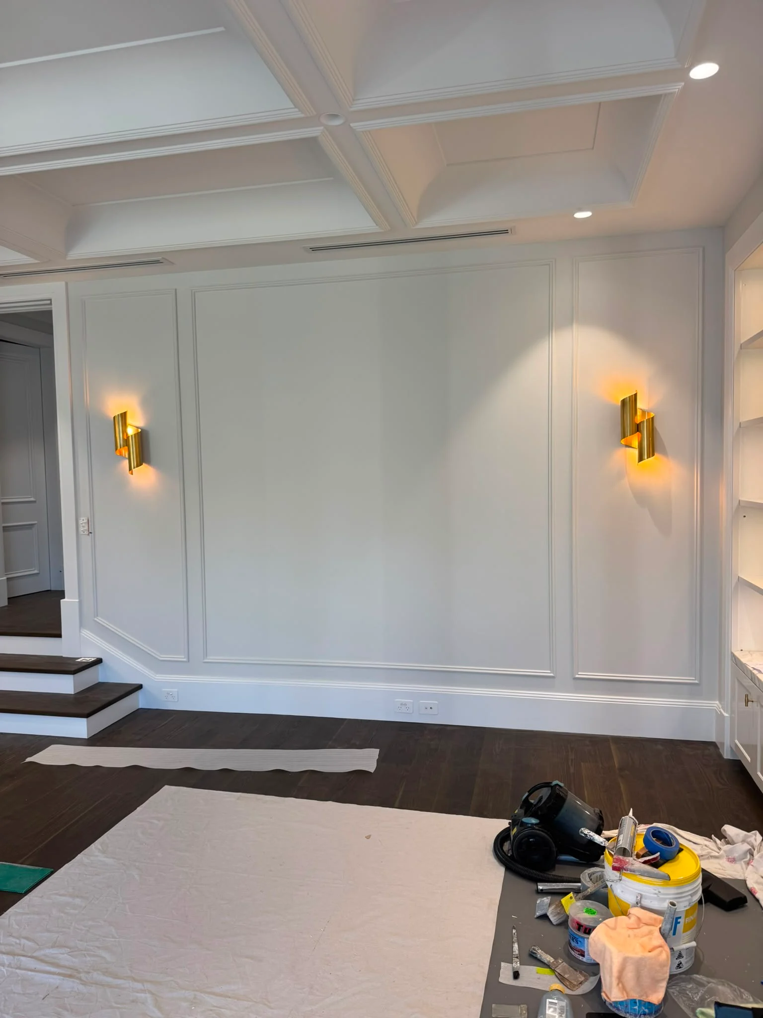 Pair of brass wall sconces on a panelled feature wall