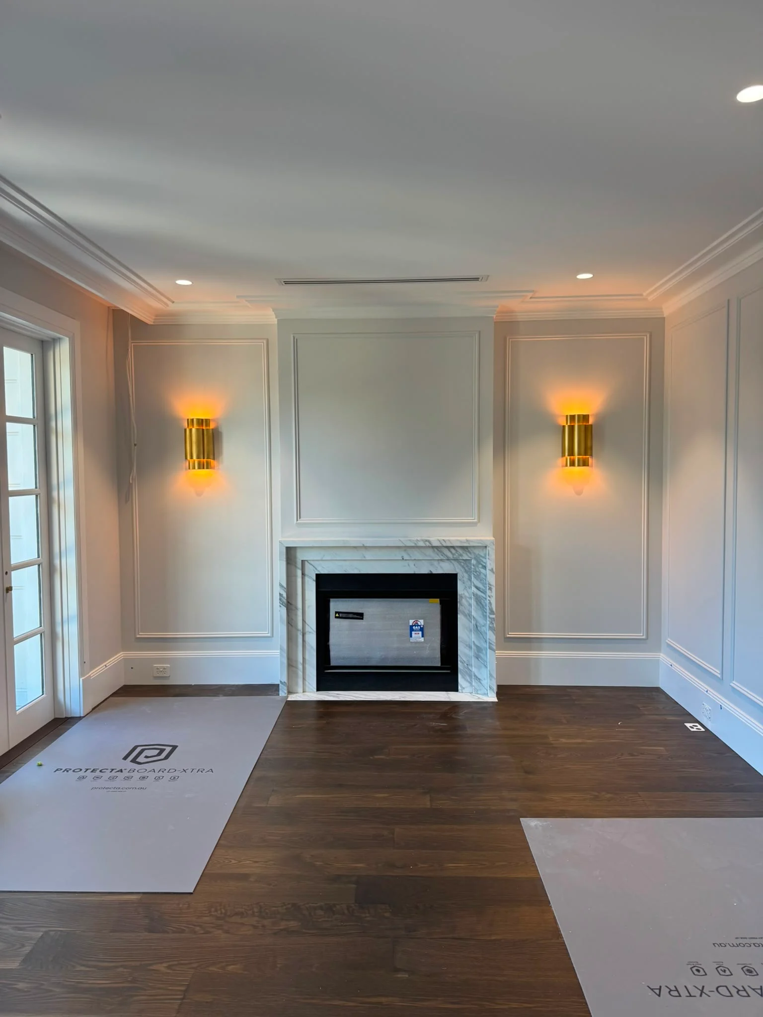 Marble fireplace framed by brass up-and-down wall sconces