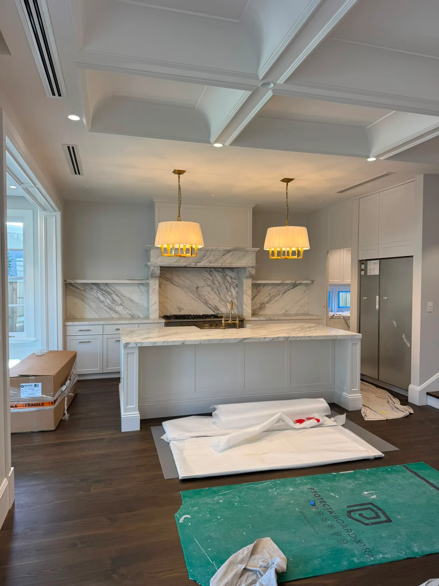 Twin gold drum pendants over a marble kitchen island