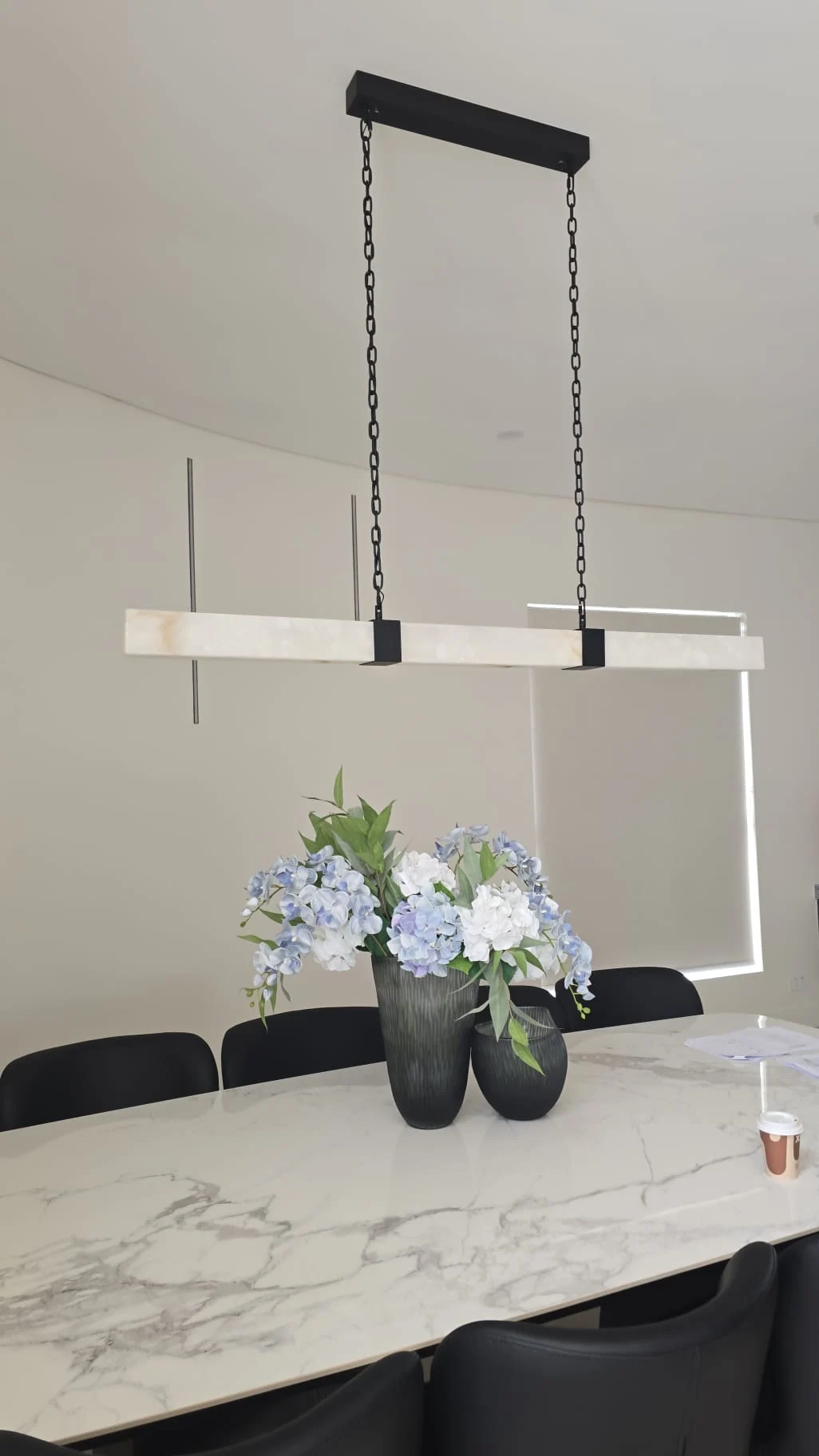Alabaster linear bar pendant over a marble dining table